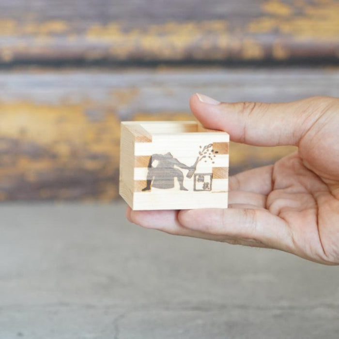 Wooden masu sake cup held in hand, engraved with Japanese figure design, part of a 3-piece set | J.Flavor × OHASHI, Japan