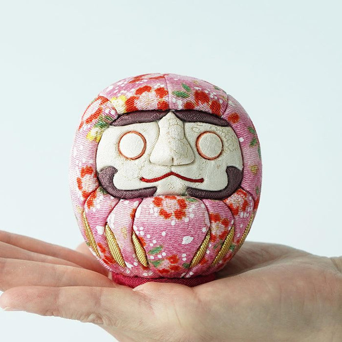Pink floral chirimen fabric daruma doll held in palm | Edo art dolls, Kakinuma Dolls