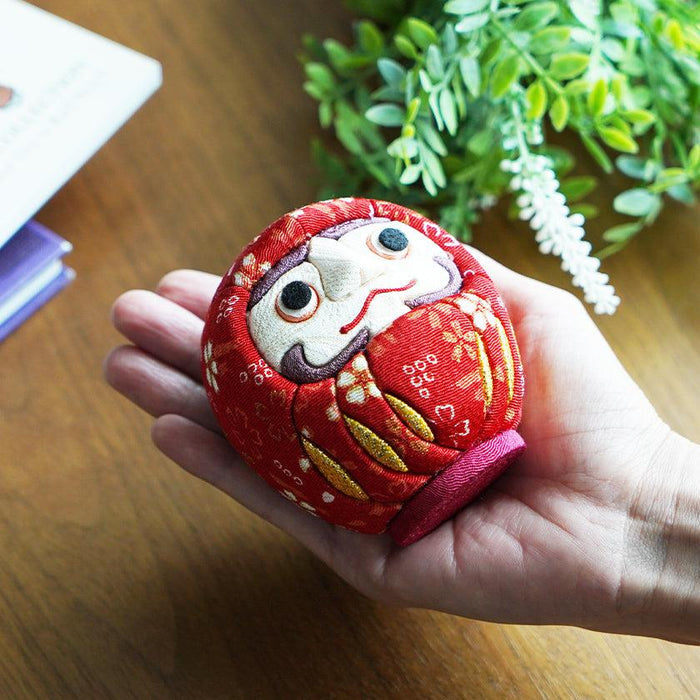 Red chirimen fabric daruma doll held in hand | Edo art doll, Kakinuma Dolls