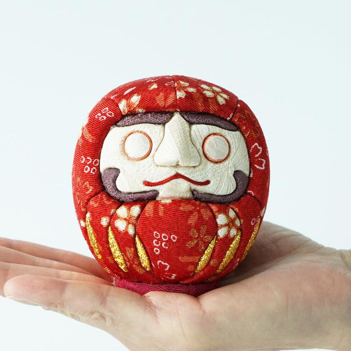Red fabric daruma doll held in hand, Edo chirimen craft | Kakinuma Dolls, Japan