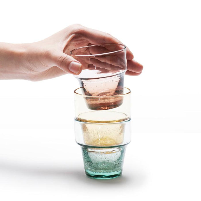 Stackable Ryukyu glass cups in pink, amber, and teal held in hand | Okinawa, aeru