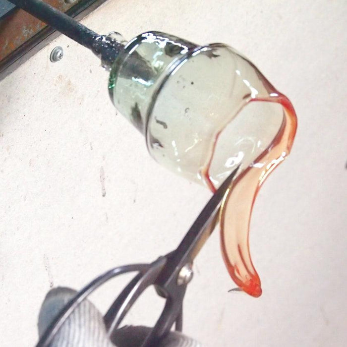 Artisan shaping molten Ryukyu glass on a blowpipe with scissors in a glassblowing workshop | Okinawa, aeru