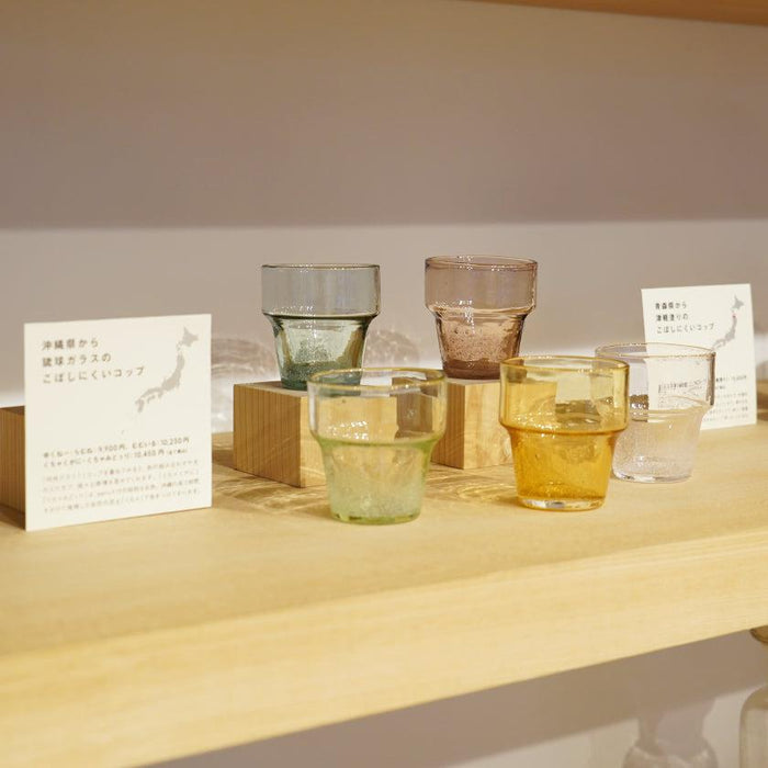 Ryukyu glass unspillable cups in multiple colors on a wooden shelf display | Okinawa, aeru