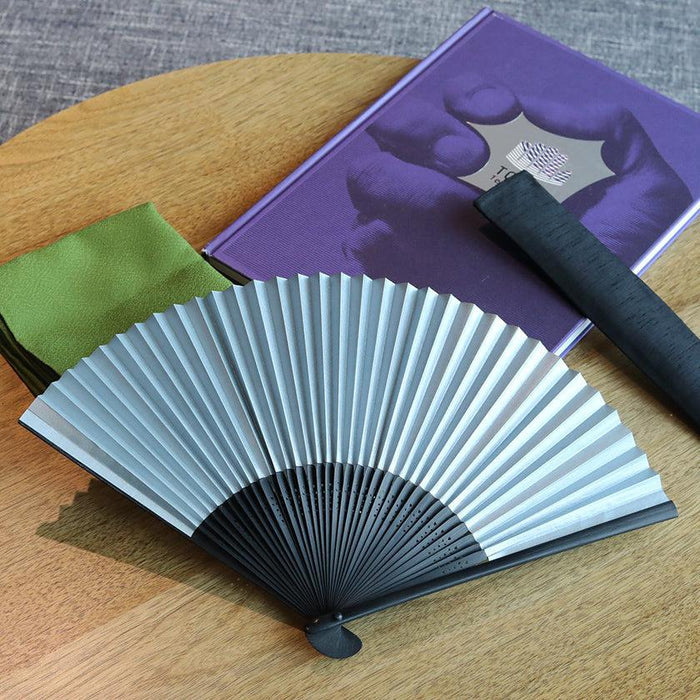 Japanese folding fan with silver paper and black bamboo ribs, open on wooden surface | Nagoya folding fan, Suehirodo