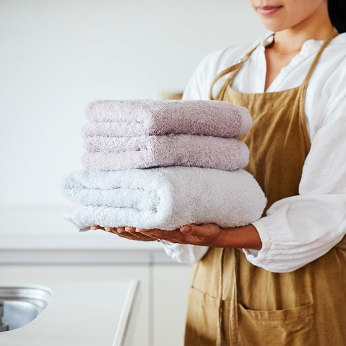 Woman holding a stack of fluffy pastel Imabari face towels | sara-la, Imabari